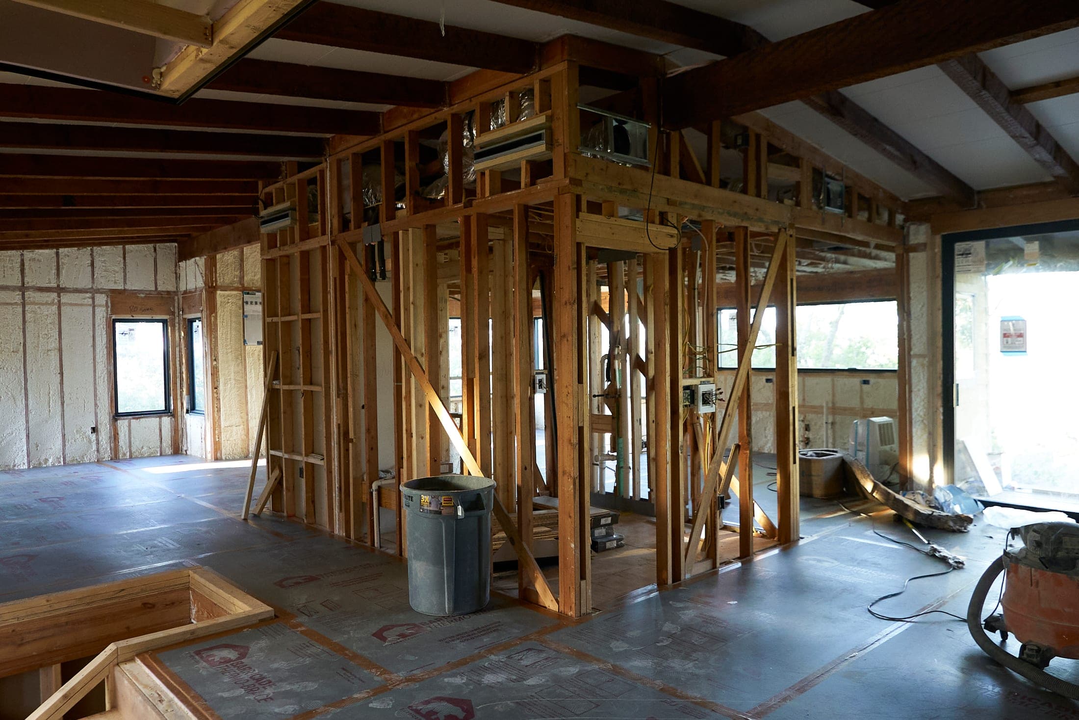 A house opened up to its framing, window openings along one wall and floor protection down