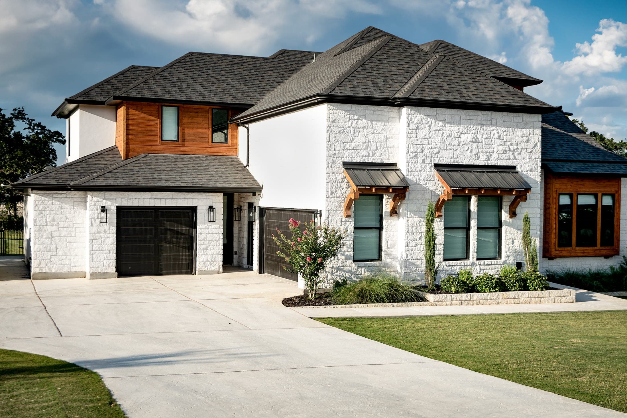 Front of the Liberty Hill Legacy home: white masonry, a wood-clad upper story and a dark roof over a two-car garage