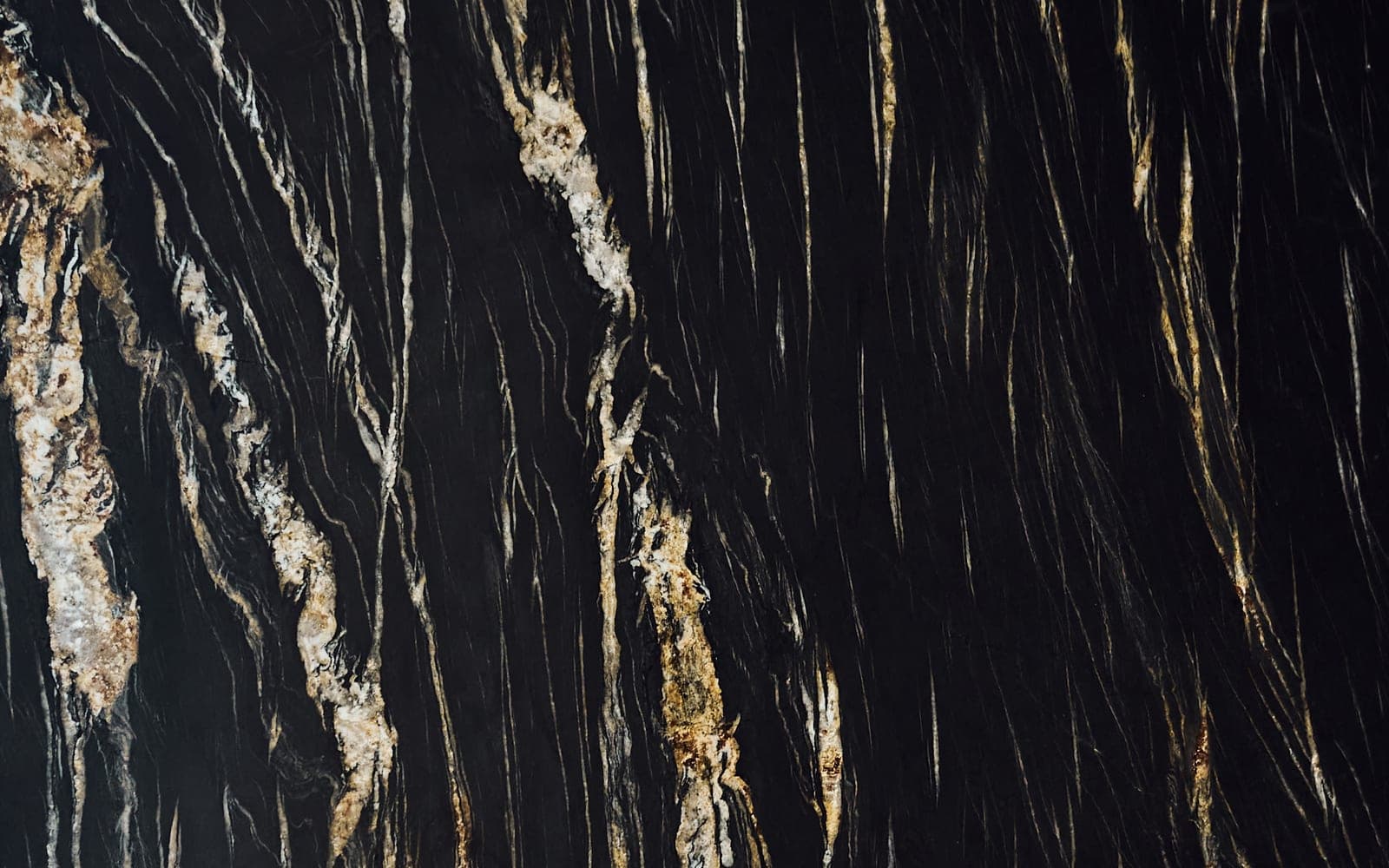 Close-up of a black stone slab threaded with gold and white veins