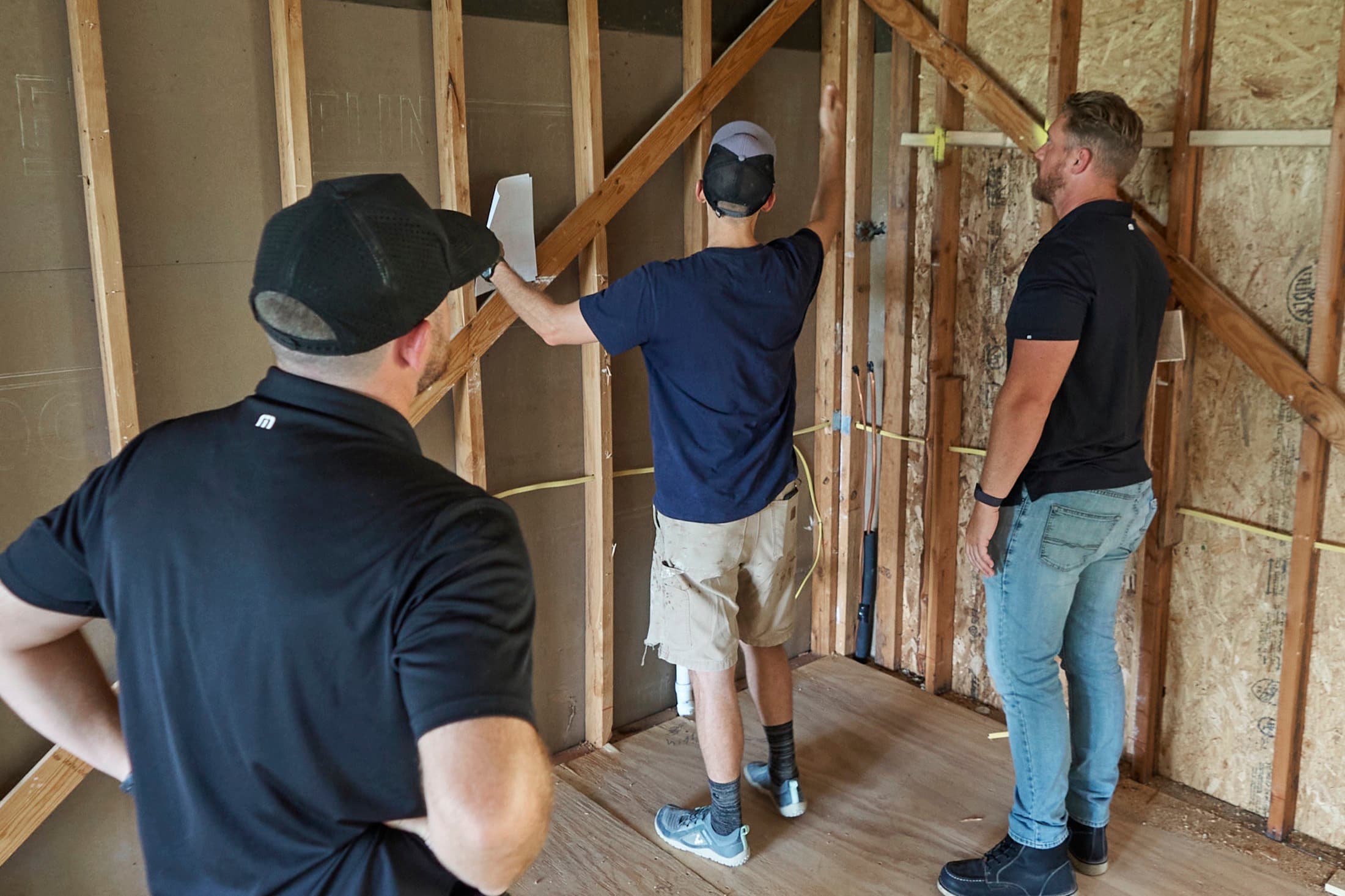 Three people walking the wall layout against open framing