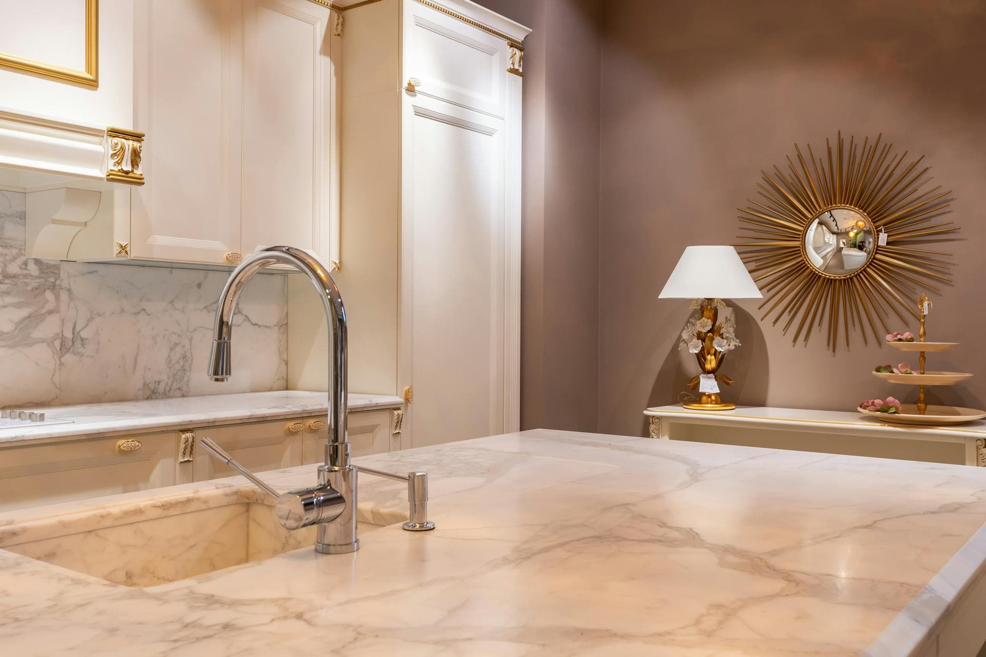 A honed marble kitchen island with dramatic grey veining in a modern luxury home interior with brass pendant lights