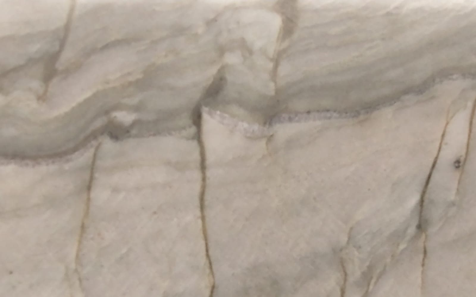 A quartzite slab on display with a band of wavy veining and natural fissures running down from it
