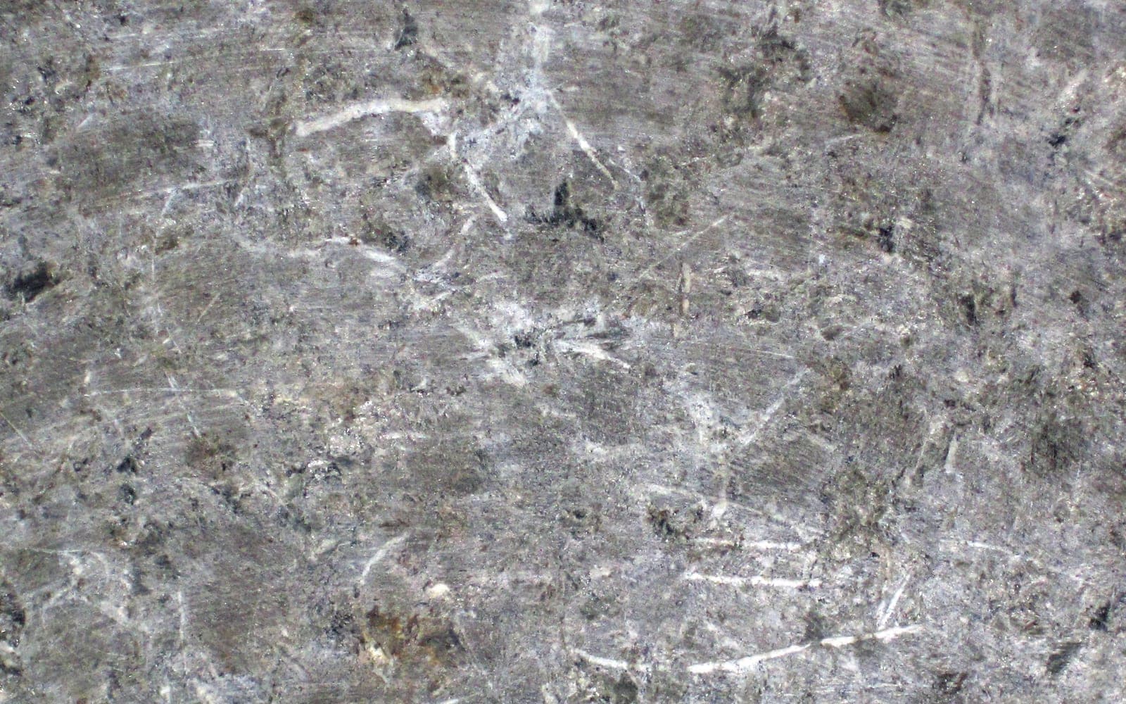 A raw block of grey soapstone from a quarry near Francestown, New Hampshire, with white streaks across the surface